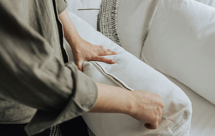 Person placing a cushion on a sofa, symbolizing moments of people getting the last laugh by delivering glorious revenge.