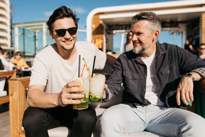 Two men enjoying cocktails outdoors, representing rich people norms and lifestyles shared by insiders on the 1 percent.