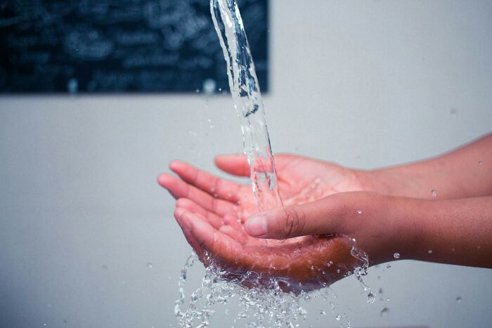 Hands catching flowing water from a faucet, illustrating a simple solution related to shipping containers problems.