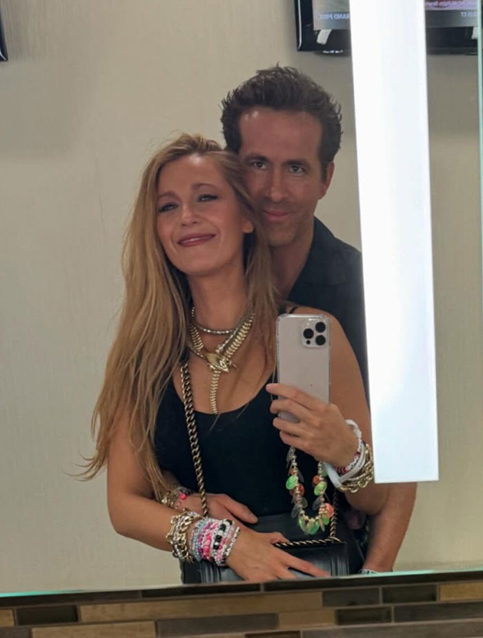 Couple taking a mirror selfie with a smartphone, related to Ryan Reynolds legal battle and texts from Justin Baldoni.