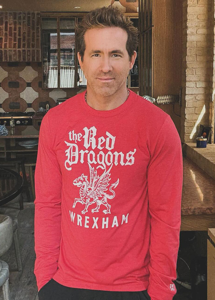 Man wearing a red long-sleeve shirt indoors, relating to Ryan Reynolds legal battle and texts from Justin Baldoni.