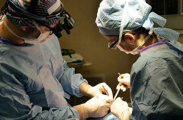 Two surgeons in scrubs and masks performing surgery on a patient, Saw images on Google