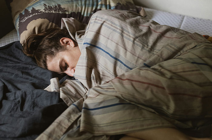 Person curled under striped blanket, face hidden, traumatized after Saw Images On Google