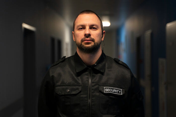 Man in a security uniform standing in a dimly lit hallway, reflecting moments people met their high school bully as adults.