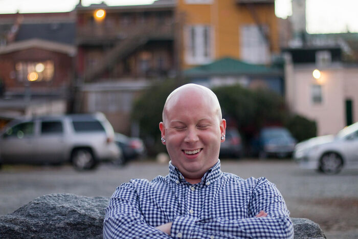 Smiling bald man in a checkered shirt outdoors, depicting confidence after meeting his high school bully adult karma moment.