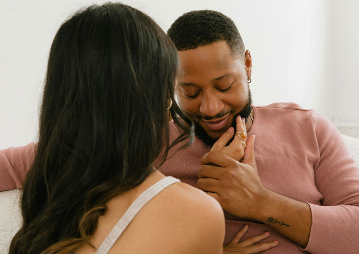 Couple sharing an intimate moment on a couch, symbolizing anonymous secrets too explosive people want to expose.