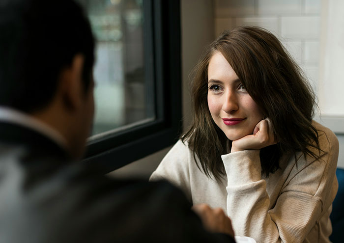 A woman sharing anonymous secrets with a man at a café, illustrating explosive people revealing hidden truths.