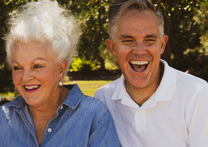 Two people laughing outdoors, representing anonymous people sharing secrets too explosive to expose.