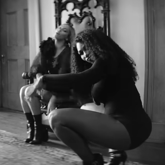 Serena Williams performing a jaw-dropping move, showcasing knees kneeing while dressed in black in an indoor setting.