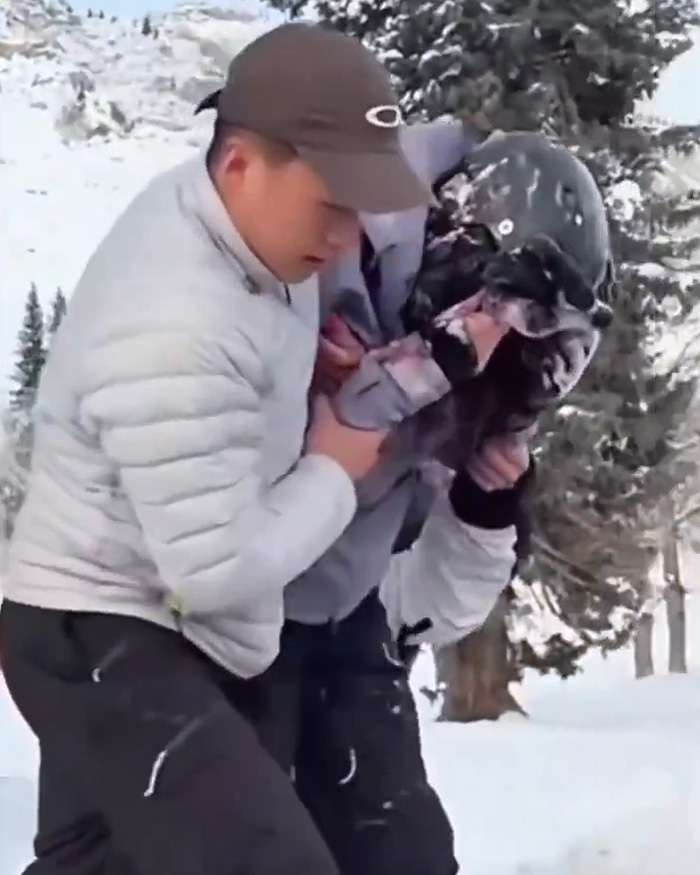 Man in winter gear helping injured skier during snow leopard attack in snowy forest setting after attempting selfie. Man in winter gear helping injured skier during snow leopard attack in snowy forest setting after attempting selfie.