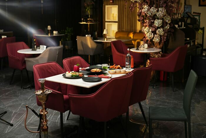 Luxurious dining setup with elegant red chairs and gourmet food, showcasing how far from reality rich people can be.