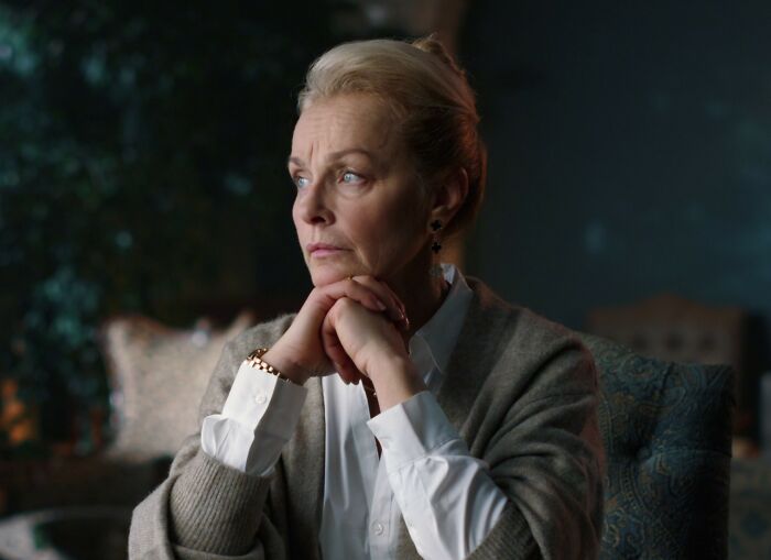 Middle-aged woman deep in thought at home, reflecting on mom inviting son&rsquo;s girlfriend to dad&rsquo;s party situation.