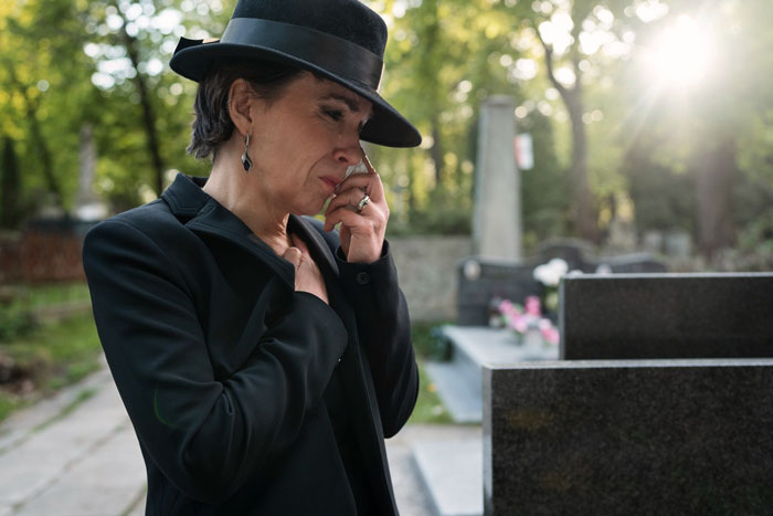 Woman mourning at a gravesite, expressing grief and loss, symbolizing the step kids mom loss money theme.