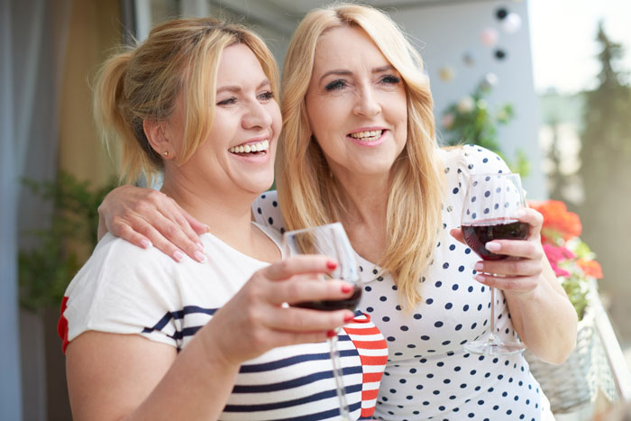 Two women smiling and holding wine glasses, representing step kids mom coping with loss of money.
