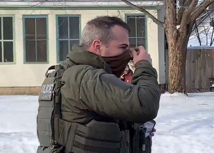 ICE agent Jonathan Ross adjusting face covering outdoors in winter, related to Stephen King backlash over post.