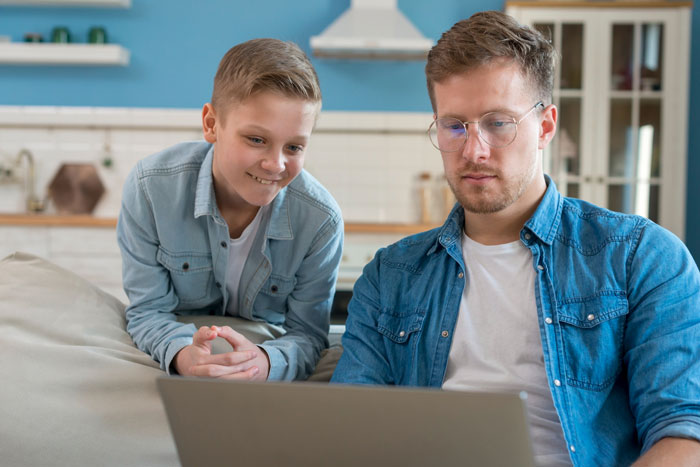 Young man and stepson managing family money and college planning together using a laptop at home.