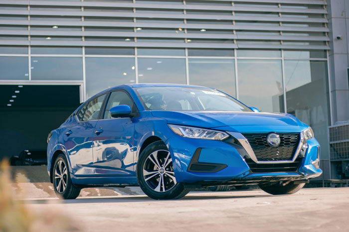 Blue sedan parked outside modern building, representing teen’s first car as a debt trap and $40k loan repayment story. Blue sedan parked outside modern building, representing teen’s first car as a debt trap and $40k loan repayment story.