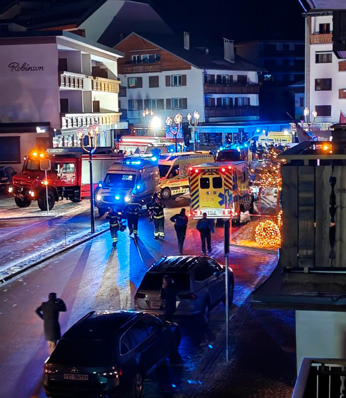 Emergency responders and vehicles at night at a ski resort after an explosion causing numerous casualties.