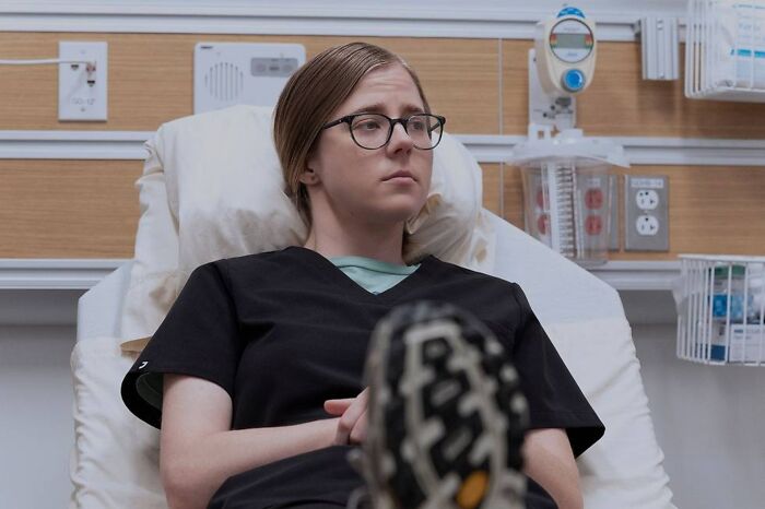 Patient wearing glasses and black scrubs lying in hospital bed, highlighting medical drama disorder portrayal. Patient wearing glasses and black scrubs lying in hospital bed, highlighting medical drama disorder portrayal.