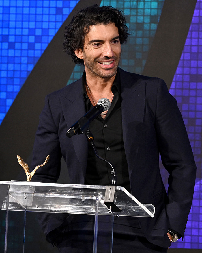 Man in dark suit speaking at a podium with microphone, relevant to Taylor Swift's wedding to Travis Kelce news report.