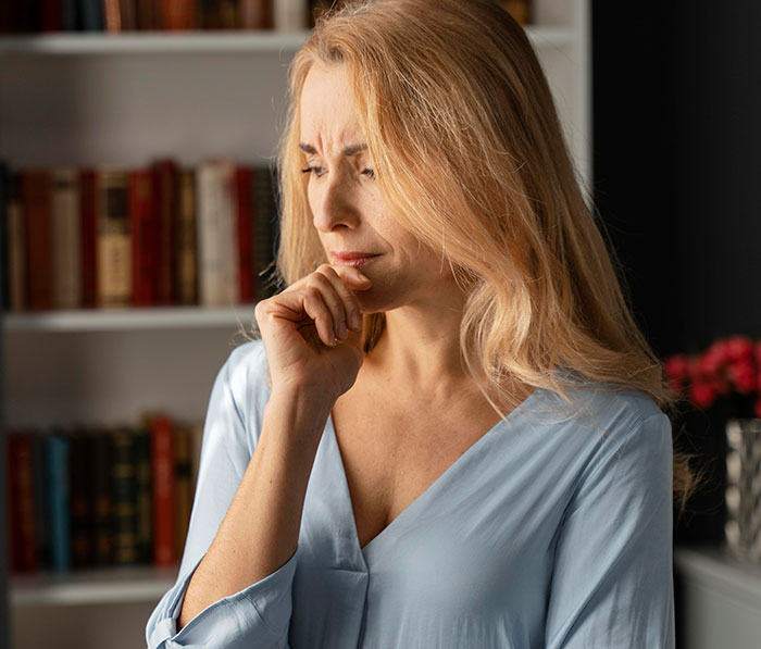 Woman looking upset and deep in thought, struggling to contain her rage over a teacher ignoring her daughter&rsquo;s emergency.