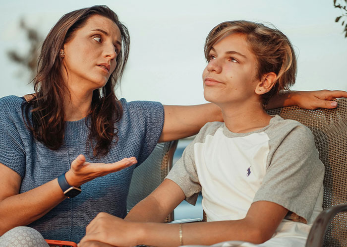 Teen and mother having a serious conversation outdoors, capturing emotions related to abandonment and hurt feelings.