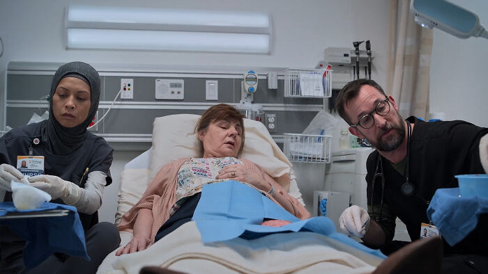 Medical staff attending to a female patient in a hospital bed, depicting a scene related to The Pitt Season 2 Tree Of Life reference.