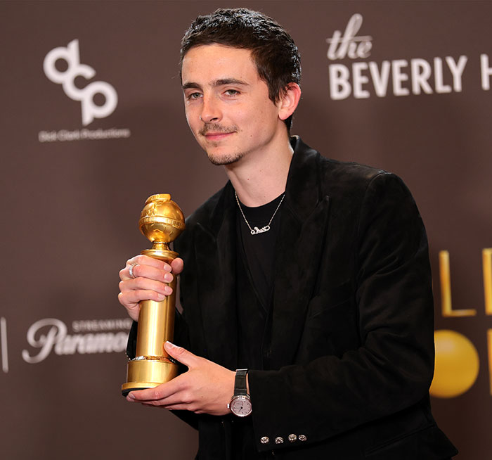 Timoth&eacute;e Chalamet holding an award, dressed in black, amid controversy over tone deaf message for fans in Ukraine backlash.