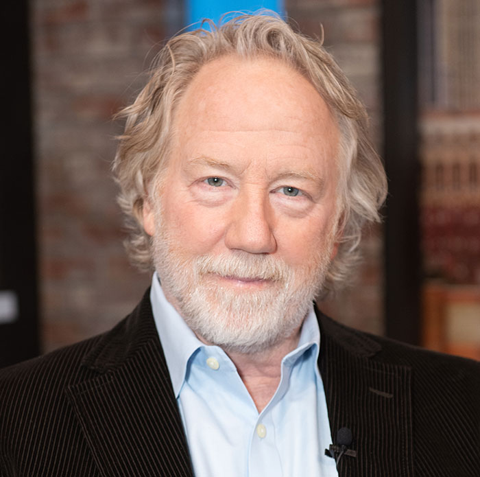 Older man with gray hair and beard wearing a blue shirt and black jacket in an indoor setting discussing Melissa Gilbert and Timothy Busfield.