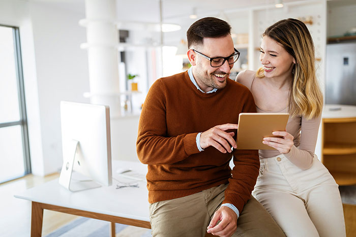 Couple smiling and looking at a tablet in a bright room, illustrating wife’s cosmetic upgrade and relationship tension. Couple smiling and looking at a tablet in a bright room, illustrating wife’s cosmetic upgrade and relationship tension.