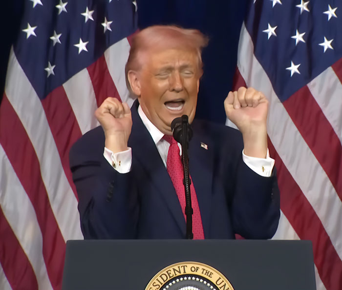 Donald Trump speaking at podium with American flags behind, showing hair with a noticeable pink tint as stylist analysis suggests.