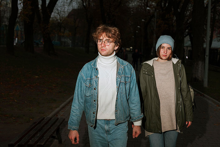 Two people walking at night in a park, appearing thoughtful while experiencing something unexplainable and surreal.