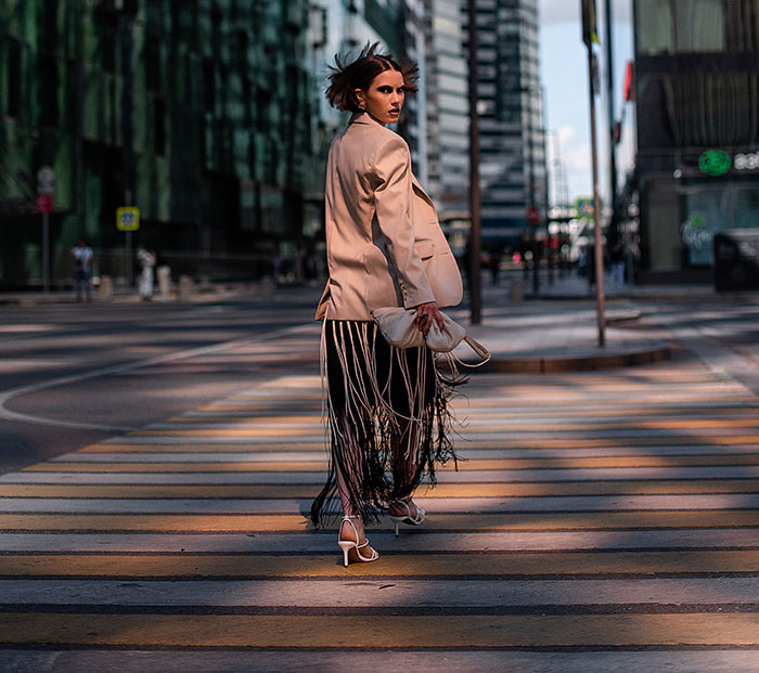 Woman walking on city street at sunset, capturing a moment that feels unexplainable and surreal to the observer.