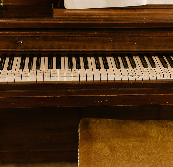 Old piano keyboard with labeled keys and a brown stool, evoking unexplainable moments some say weren’t a dream.