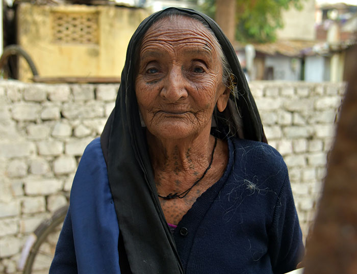 Elderly woman with deep wrinkles wearing a black headscarf, embodying stories of unexplainable sightings and experiences.