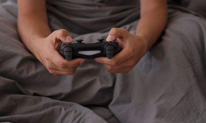 Person holding a game controller while sitting in bed, representing moments of seeing something unexplainable.