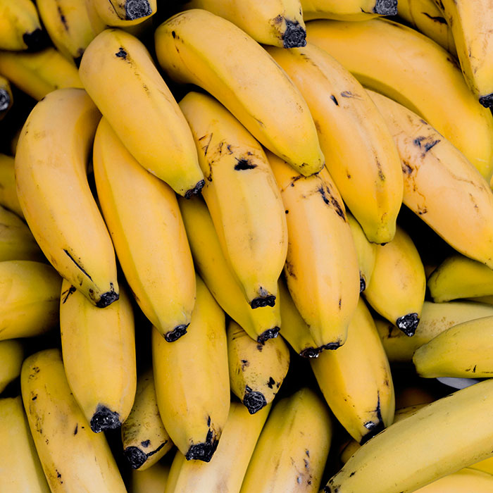 A close-up of ripe yellow bananas with dark tips, showcasing an unexplainable natural pattern and texture.