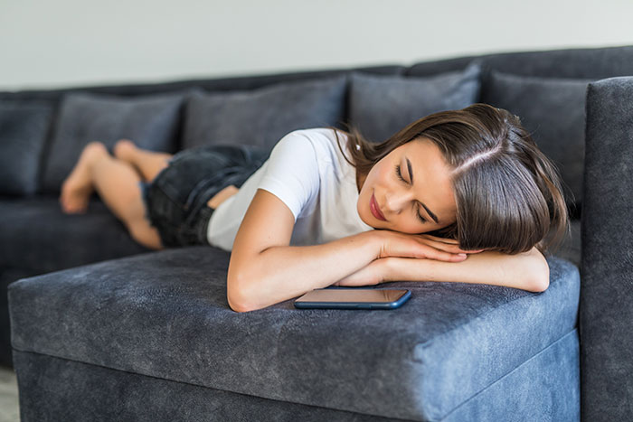 Young woman lying on a couch with eyes closed, appearing to have an unexplainable experience beyond a dream.