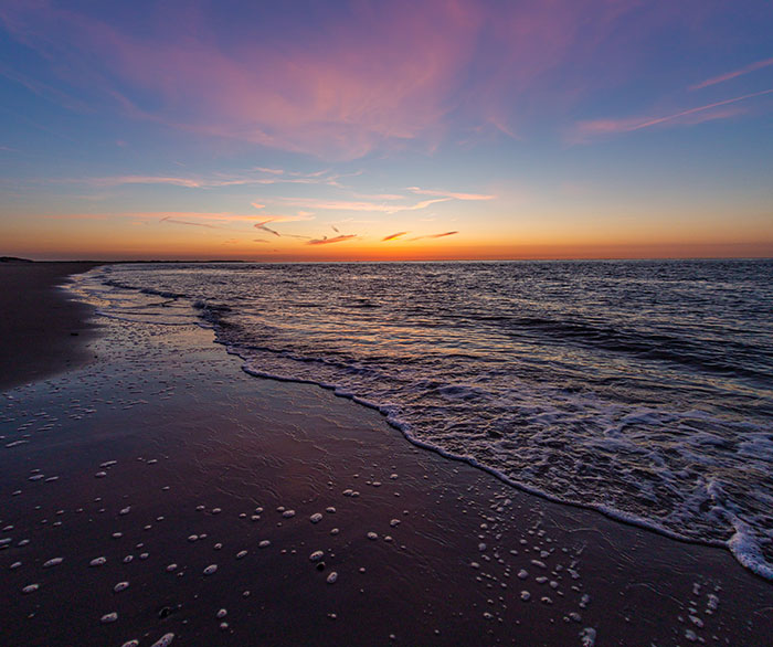 Ocean shore at sunset with colorful sky and calm waves, evoking a sense of unexplainable sighting by the beach.