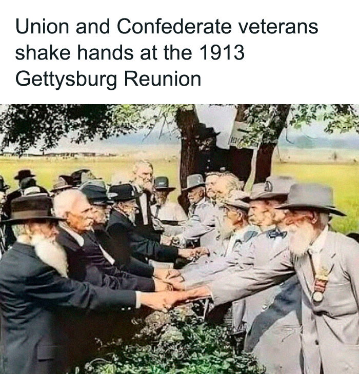 Union and Confederate veterans shaking hands at the 1913 Gettysburg Reunion in a historic US history photo.
