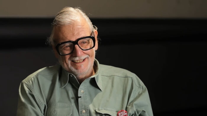 Elderly man with glasses smiling during an interview, illustrating moments when people met their idols in real life.