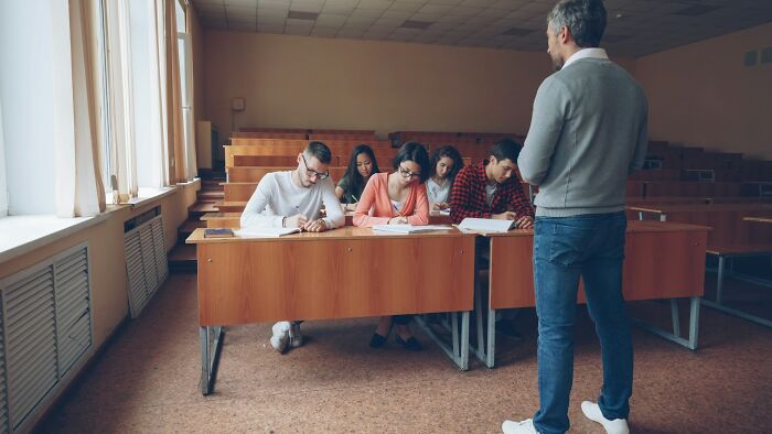 Students sitting in class while a teacher stands in front, illustrating weird teacher behavior witnessed in class.
