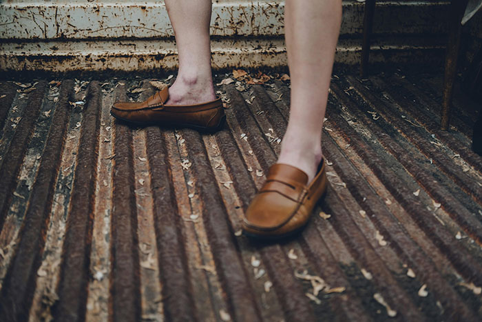 Close-up of person’s feet wearing brown loafers standing on rusty corrugated metal surface, illustrating attraction ending ick moment.