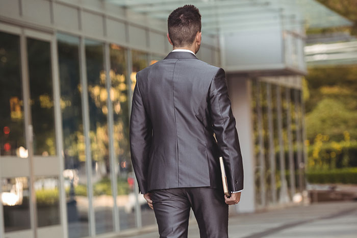 Man in a gray suit walking outside a modern building, symbolizing moments when attraction ended due to a weird ick.
