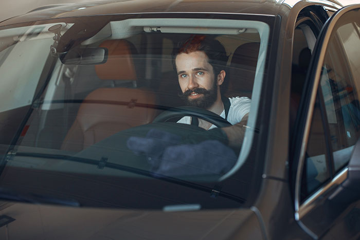 Man with beard sitting in car looking thoughtful, illustrating moments when attraction ended due to unexpected ick feelings.