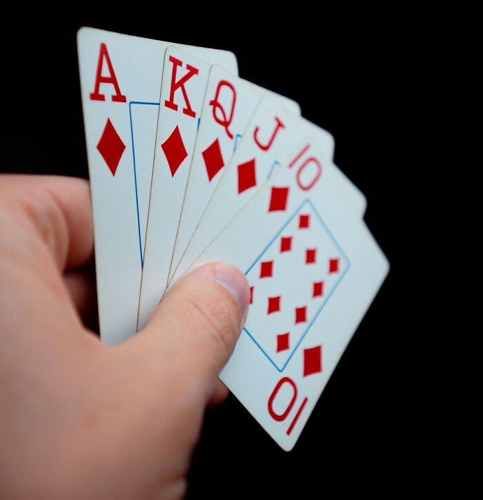 Hand holding a royal flush of diamonds cards, symbolizing surprising intelligence in a game strategy.