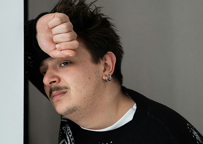 Man looking stressed and leaning against wall, reflecting on secretly playing video games and buying Star Wars figures.