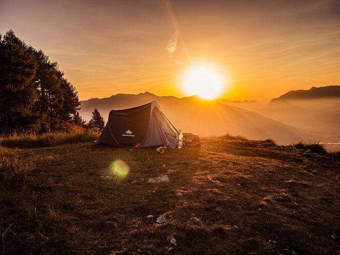 Tent set up at sunset on a mountain top, highlighting a strange light phenomenon in a weird unexplained outdoor scene.