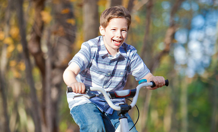 Young boy riding a bike in a park, smiling and enjoying a sunny day, capturing a moment people witnessed something weird
