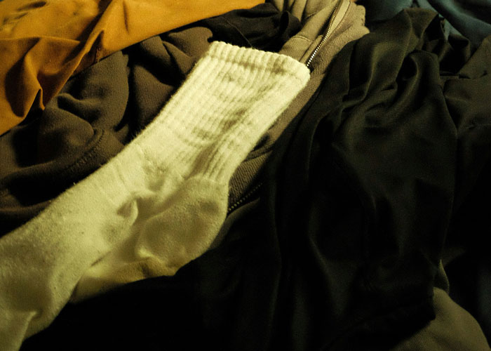 White fancy designer sock lying on dark clothing, hinting at man trying to convince girlfriend he didn&rsquo;t cheat at home.
